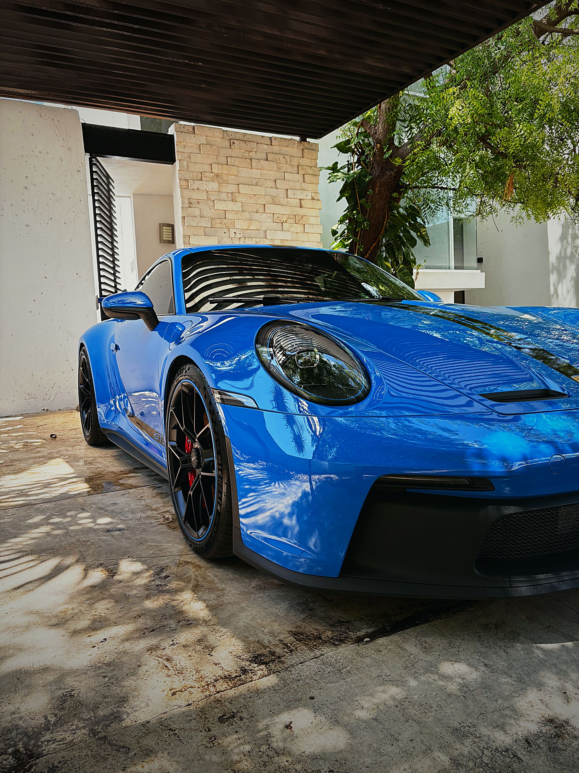 Porsche 911 GT3 azul recién detallado bajo una cochera